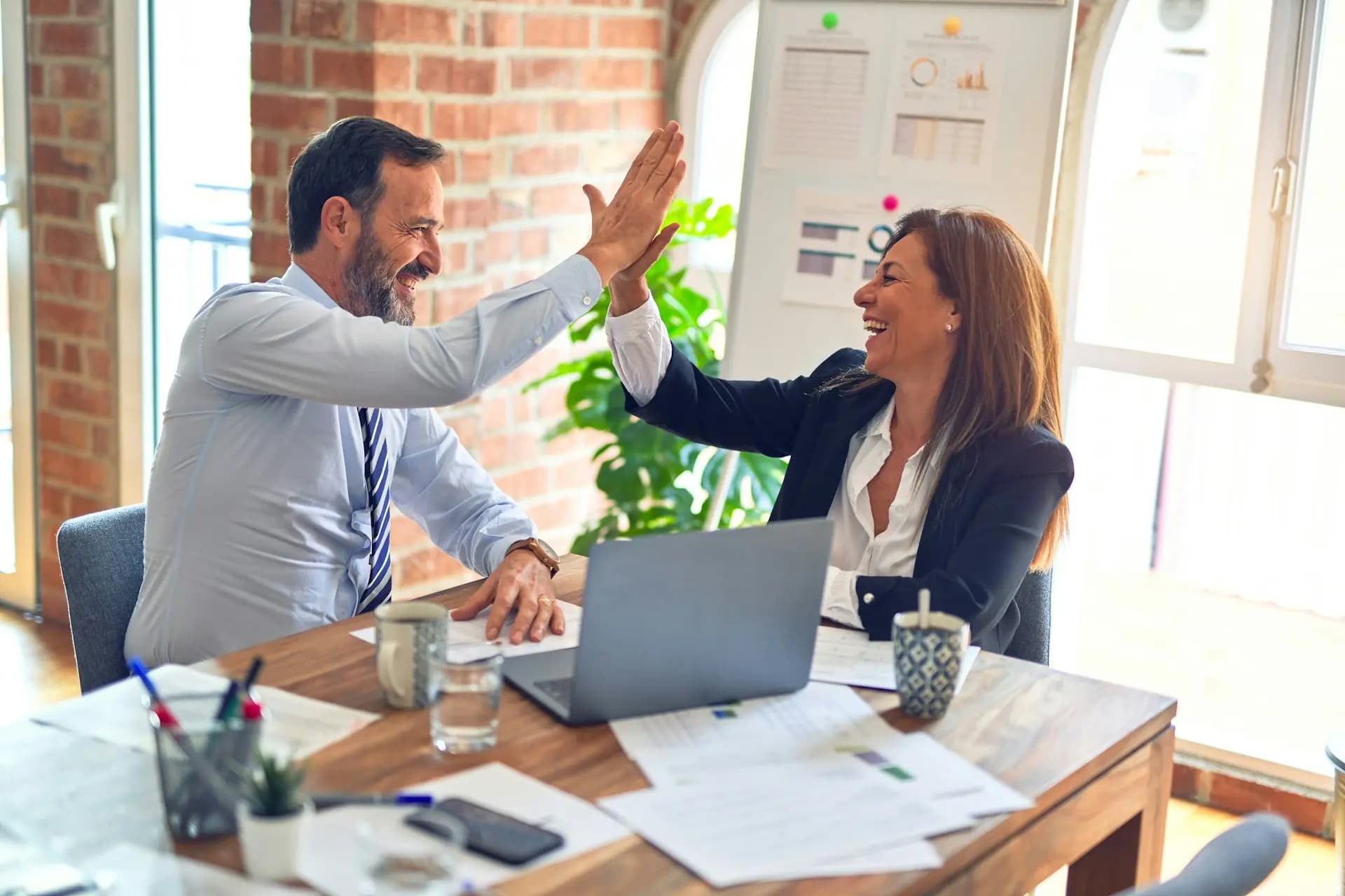 A partner and a client celebrating good news at a bright office table